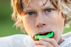 blond boy with green mouth guard